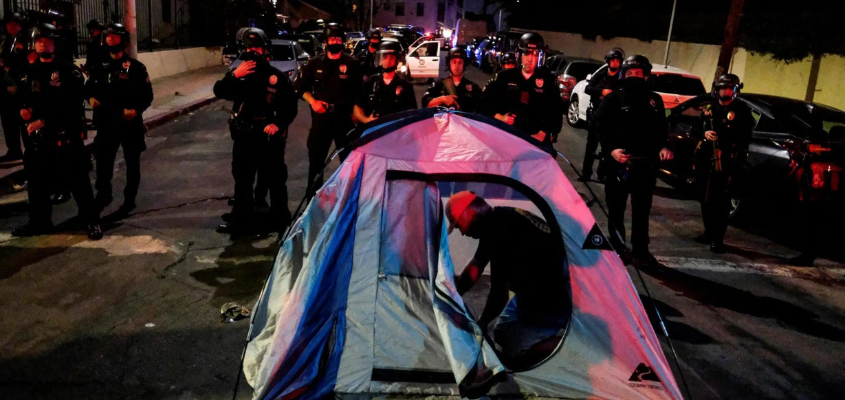 A man sets up a tent in front of police