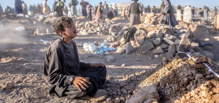 An Afghan boy mourns next to a grave of his little brother who died due to an earthquake.