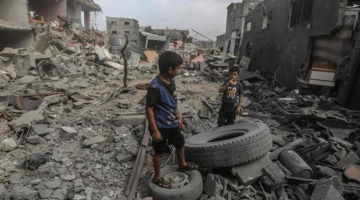 Palestinian children stand amid the rubble of destroyed buildings